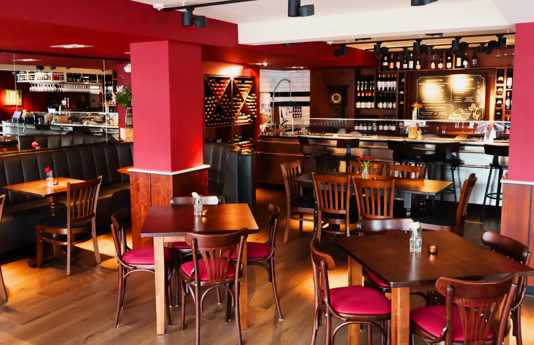 The dining room at Chez Bernard, with red pillars, bentwood chairs and the wine wall behind