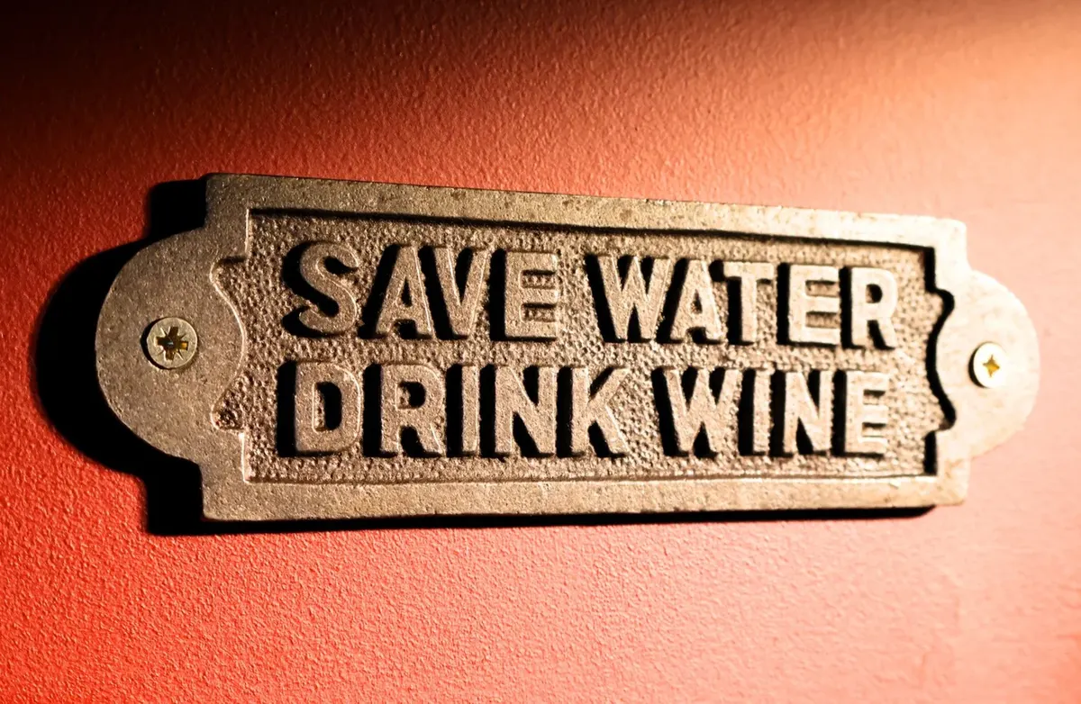 A brass plaque reading Save Water Drink Wine